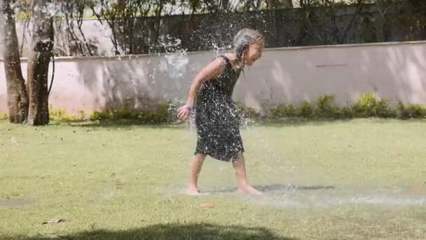 행복한 소녀는 공원에서 물 제트 아래 웅덩이에서 재미를. — 비디오