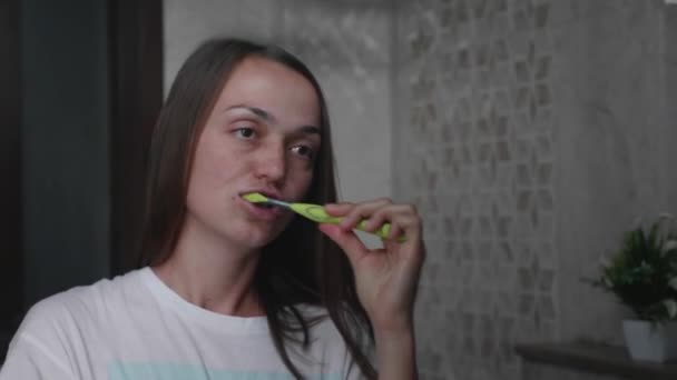 Young woman is brushing her teeth with a toothbrush in bathroom. — Stock Video