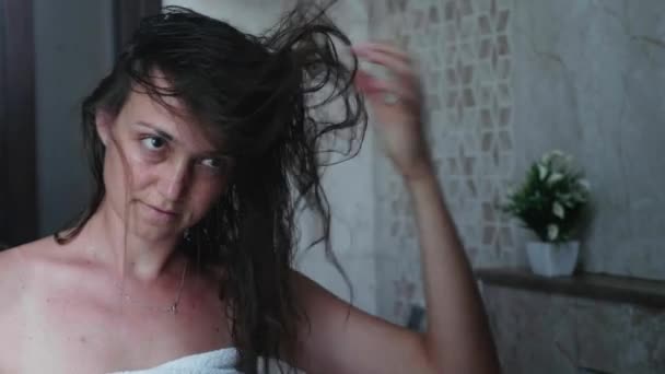 La joven se seca el cabello con un secador de pelo. Retrato grabado en reflejo de espejo — Vídeo de stock