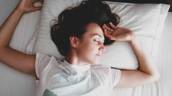 Junge Frau schläft am Morgen auf dem Bett. — Stockfoto