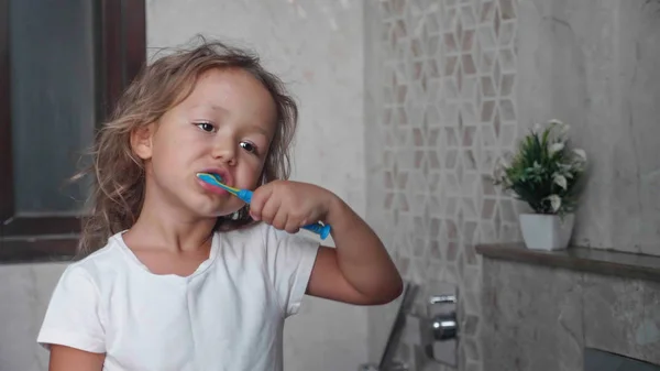 Little child girl is brushing her teeth with toothbrush in bathroom. — Stock Photo, Image