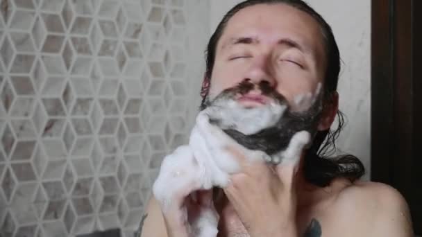 L'uomo si lava la barba con shampoo e schiuma sotto la doccia . — Video Stock