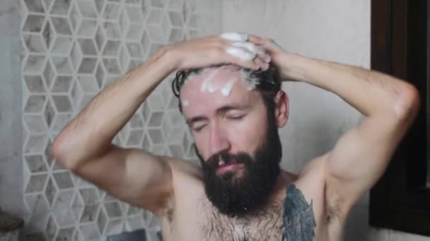 Young bearded man is washing head in a shower at home, close-up — Stockvideo