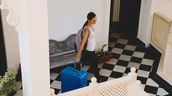 Young woman with suitcase check-in to the hotel.