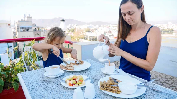 Familjen har en frukost tillsammans på terrassen med vacker utsikt över bergen — Stockfoto