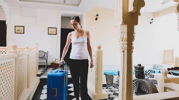 Young woman with suitcase check-in to the hotel. — Stockfoto