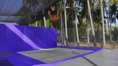 Erkek jimnastikçi palmiye ağaçları arka plan trambolin açık eğitim.