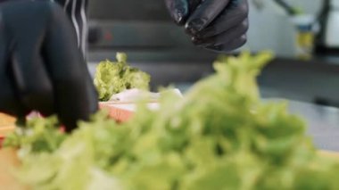 Restoranda şef marul, jambon ve peynir ile bir sandviç pişirin.