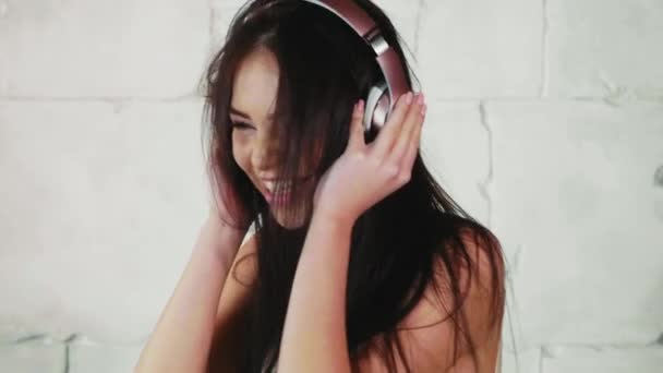 Joven mujer feliz está escuchando música en los auriculares, agitando la cabeza y bailando — Vídeos de Stock