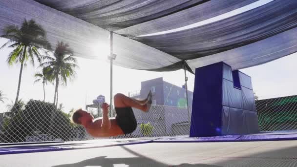 Mužská gymnastka cvičí na trampollince. Člověk skáče venku v pomalém pohybu. — Stock video