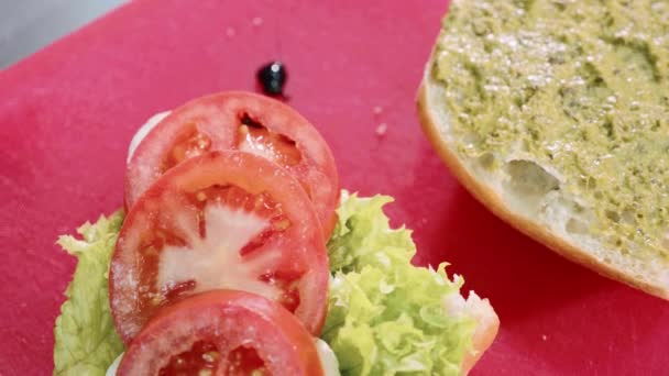 Kırmızı plastik kesme tahtası üzerine teriyaki soslu vegan burger dökme. — Stok video