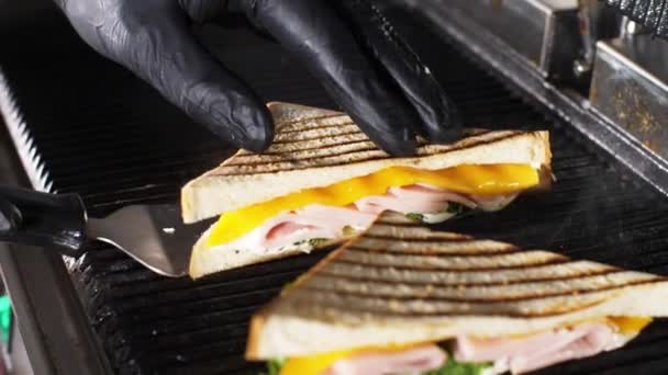 Chef toma sándwiches calientes de la parrilla eléctrica usando un cuchillo . — Vídeos de Stock