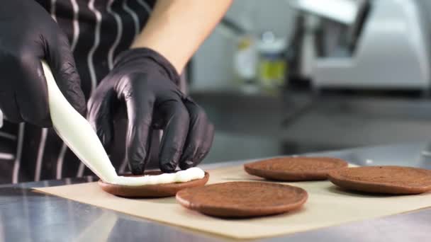 Chef de pastelaria está enchendo biscoitos com creme e geléia fazendo pequenos bolos . — Vídeo de Stock