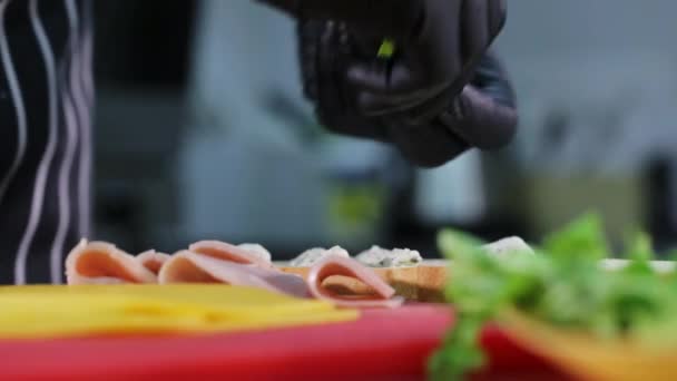 Человек кладет салат на хлеб во время приготовления сэндвича . — стоковое видео