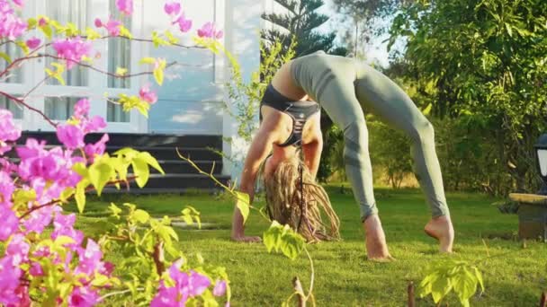 Fiatal nő professzionálisan bridzs jóga pózt csinál a háza hátsó udvarán.. — Stock videók