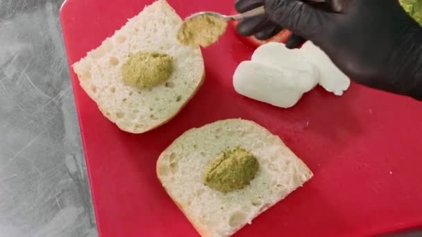 Chef está cocinando sándwich vegetariano con salsa, mozzarella, lechuga y tomates — Vídeo de stock