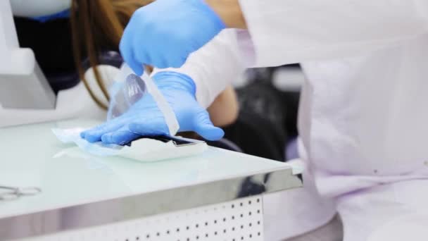 Dentysta w niebieskie rękawice lateksowe otwiera opakowanie z dentystycznych narzędzi sterylnych, zbliżenie. — Wideo stockowe