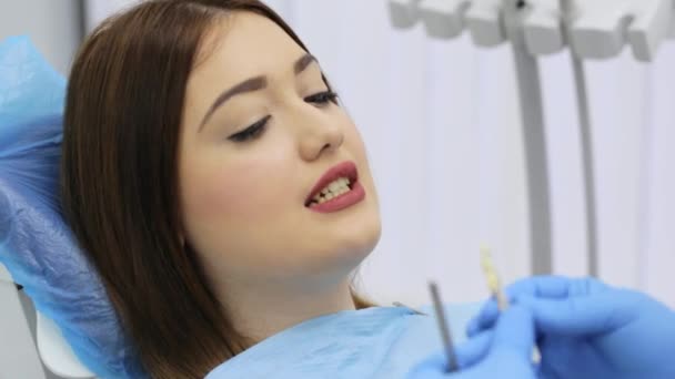 歯の色のサンプルが付いている歯科医は女性の忍耐強い歯のための陰を選ぶことである — ストック動画
