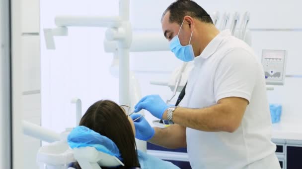 Dentista faz exame preventivo de mulher jovem sentada em cadeira dentária — Vídeo de Stock