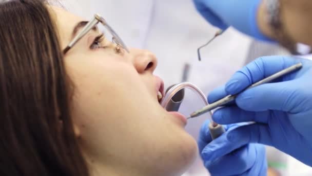 Stomatologul verifică dinții femeilor cu oglindă dentară — Videoclip de stoc