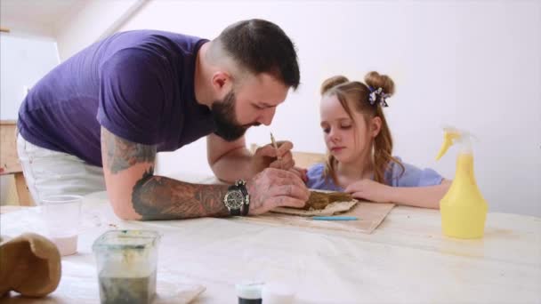 Teacher explains and shows his pupil girl how to modeling a toy from clay. — Stock Video