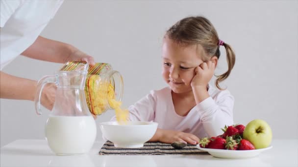 Klein meisje wacht haar ontbijt cornflakes met melk. — Stockvideo