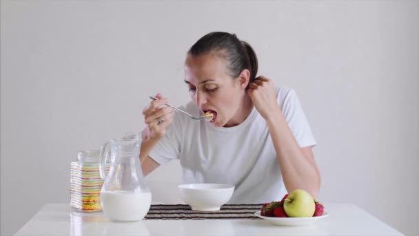 Giovane donna sta mangiando cornflakes con latte per colazione con appetito . — Video Stock