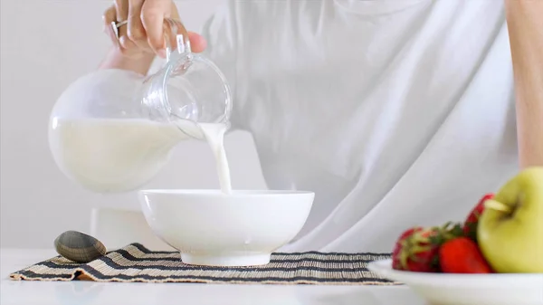 Mujer joven está desayunando copos de maíz con leche y frutas . —  Fotos de Stock