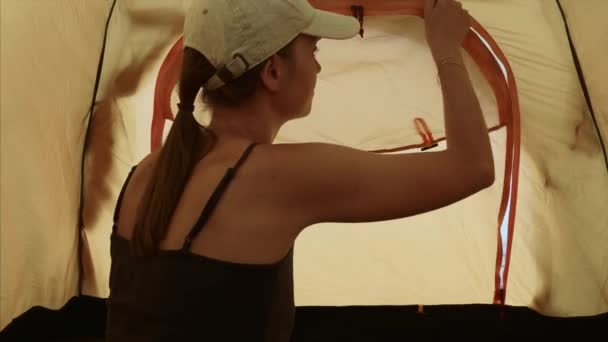 Vrouw ritst de tent binnen en kijkt naar zee stretching haar armen in de ochtend. — Stockvideo