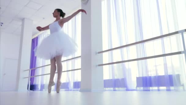 Νεαρή μπαλαρίνα με άσπρα παπούτσια και κλακέτες που στριφογυρίζουν στο χορό στην τάξη του μπαλέτου. — Αρχείο Βίντεο
