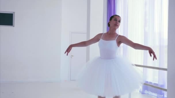 Ballerina w białym Tutu i pointes kręci się w tańcu w klasie baletowej. — Wideo stockowe