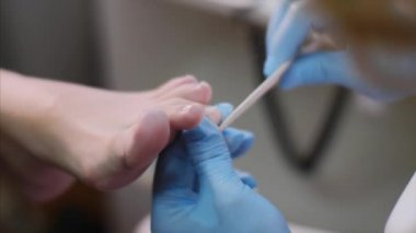 Pedikürcü güzellik salonunda tırnak dosyası kullanarak müşterilerine ayak tırnakları çivi modelleme olduğunu.