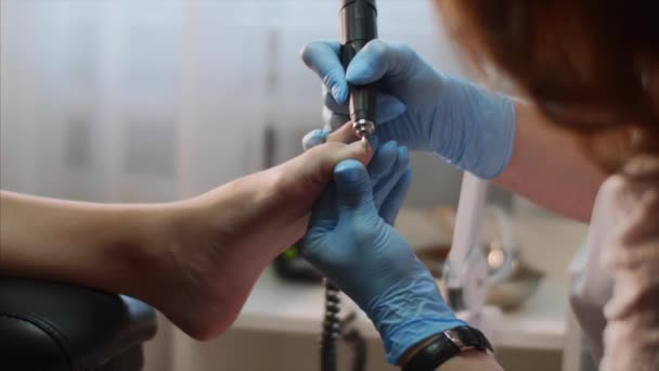 Maître pédicure en gants bleus fait pédicure quincaillerie dans un salon de beauté . — Video