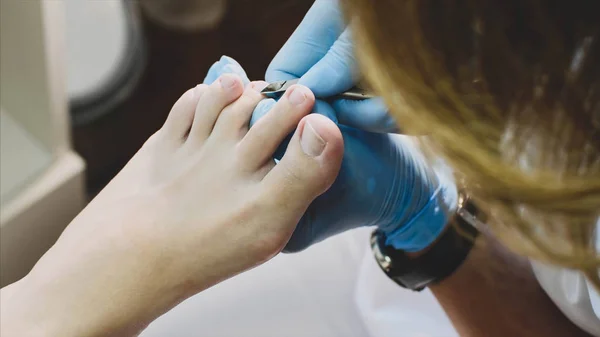 Pedicurist tnie naskórka na palec z Szczypce do paznokci sprawia, pedicure w salonie piękności. — Zdjęcie stockowe