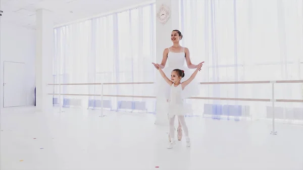 Profesora de ballet con niñita entrenando pasos de puntillas en pointes cogidas de la mano . — Foto de Stock