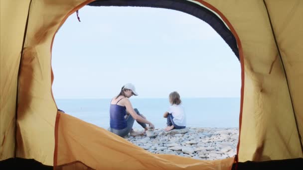 Mamma sta costruendo una torre di pietre con la sua piccola figlia sulla spiaggia di mare . — Video Stock