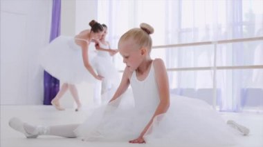 Beyaz tutu çocuk kız balerin bale dersi streç egzersizleri yapıyor.