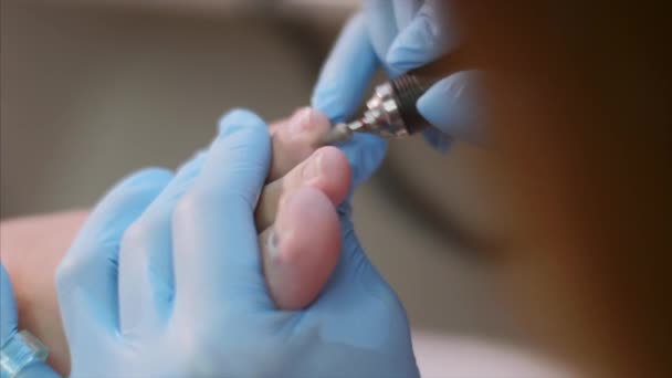 Maestro pediatra in guanti blu rende pedicure hardware nel salone di bellezza . — Video Stock