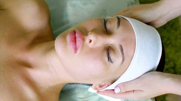 Cosmetologist puts on headband on young woman before treatment in spa salon. — Stock Photo, Image