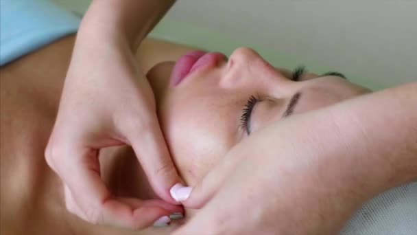 Masaż terapeuta kosmetyczka sprawia, że masaż policzkowy dla kobiety w klinice piękności. — Wideo stockowe