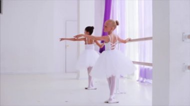 İki balerin çocuk performans dans elemanları barre standı yakınında ayakta.