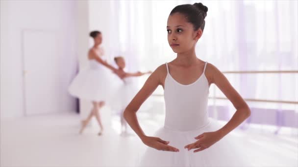 Девушка-балерина стоит в балетной позе. Учитель с девушкой на заднем плане . — стоковое видео
