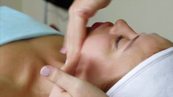 Massagetherapeutin Kosmetikerin massiert Wangen für Frau im Schönheitssalon. — Stockvideo