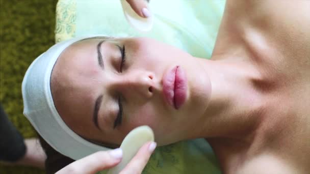 Femme reçoit un massage facial avec des tranches de paraffine dans le centre de spa de cosmétologie . — Video