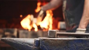 Örs ve arka planda işçinin elleri üzerinde Hammer ateş ile fırında ahşap koymak.