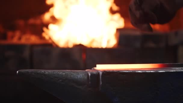 Blacksmith hitting hot metal bar with massive hammer on anvil in slow motion. — Stock Video