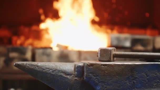 Молоток на наковальне в кузнице на огненном фоне, в котором рабочий выбрасывает мусор . — стоковое видео