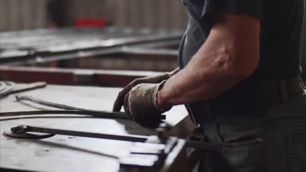 Master bends metal bar in vice on workplace for manufacture of metal structures. — Stock Video