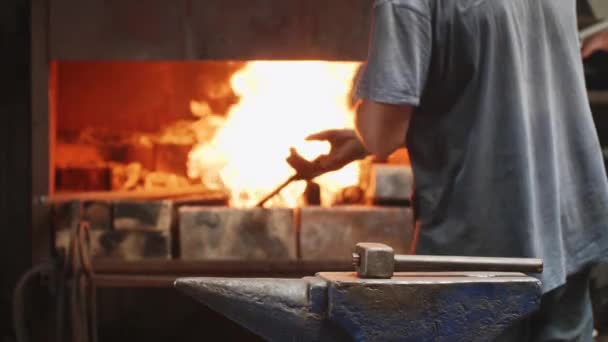 Travailleur met des gants et mélange le bois dans le four en utilisant le poker dans la forge .