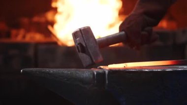 Demirci yavaş çekimde örs üzerinde büyük çekiç ile sıcak metal bar isabet.